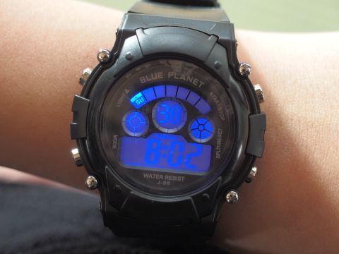 300円の腕時計はブルーのバックライト付き。中央には秒の表示、その上には曜日を表示します。ストップウォッチとアラーム機能も付いています。