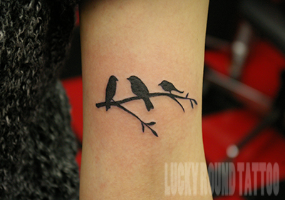 枝にとまる鳥のシルエットのタトゥー Lucky Round Tattoo